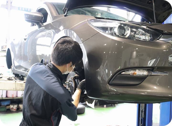 リフトアップされた車を整備する作業員