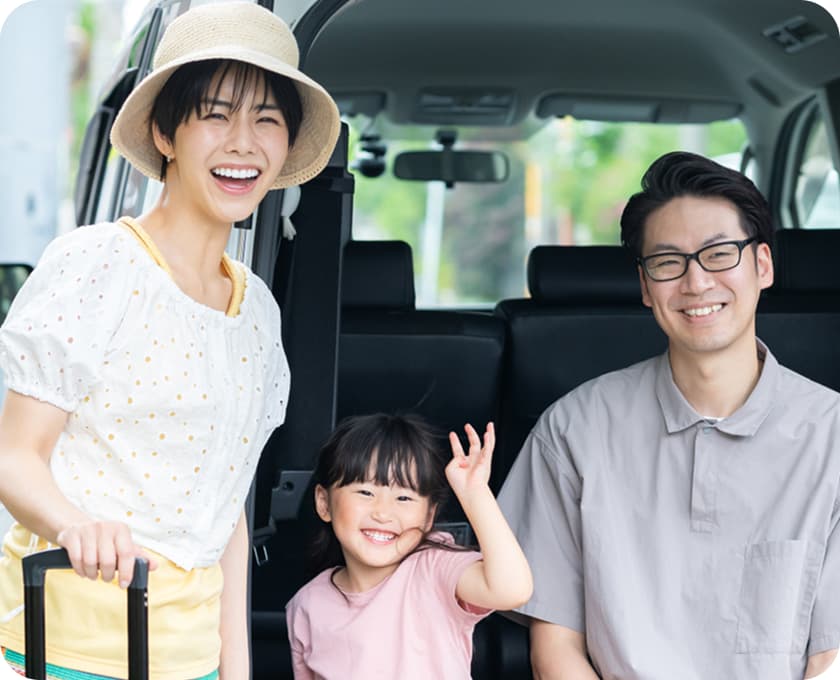 車の前で笑顔を見せる家族