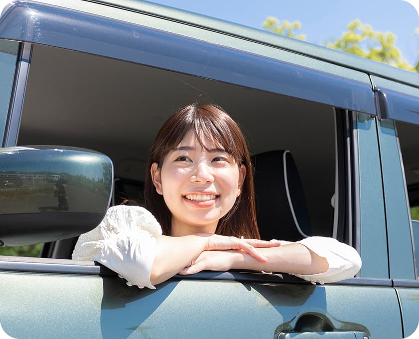 車の窓から顔を出して笑顔を見せる女性