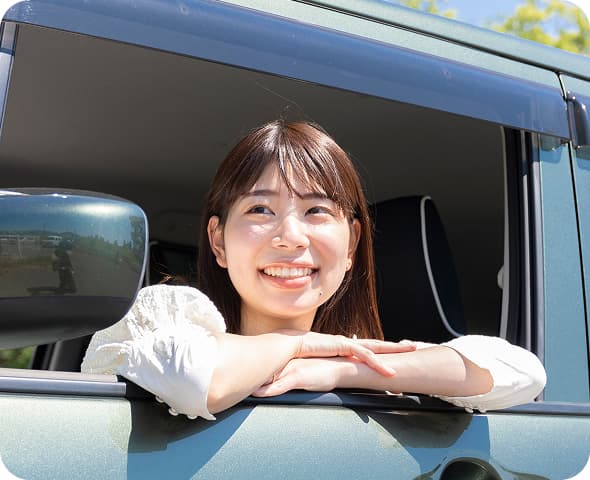 車の窓から顔を出して笑顔を見せる女性